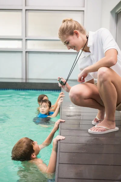 Pretty swimming coach showing boy his time — Stock Photo, Image