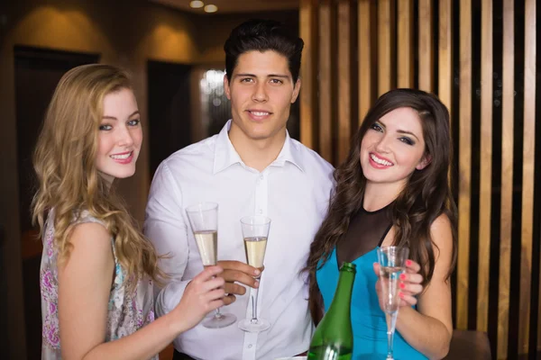 Amigos atraentes sorrindo para a câmera segurando champanhe — Fotografia de Stock