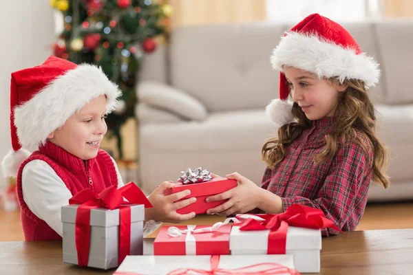 Hermanos festivos sonriendo a sus regalos — Foto de Stock