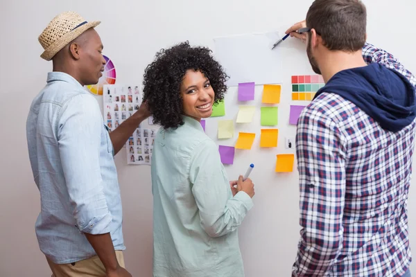 Team kijken naar kleverige nota's op de muur — Stockfoto