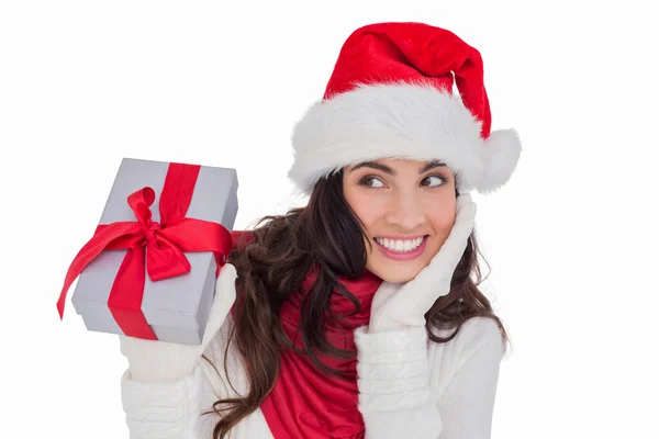 Surprised brunette in santa hat holding gift — Stock Photo, Image