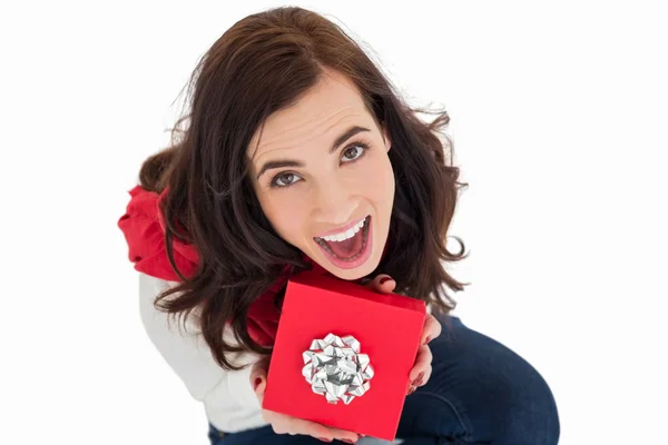 Excited brunette sitting holding red gift — Stock Photo, Image