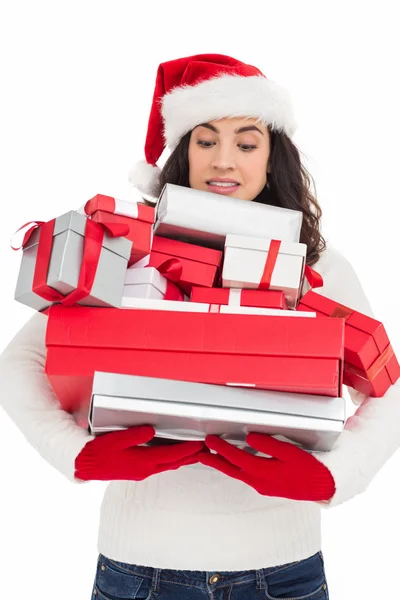 Stressed brunette in santa hat holding pile of gifts — Stock Photo, Image