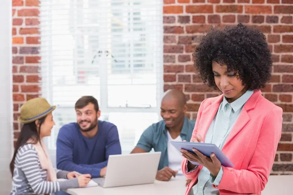 Woman using digital tablet with colleagues behind in office — Stock Photo, Image