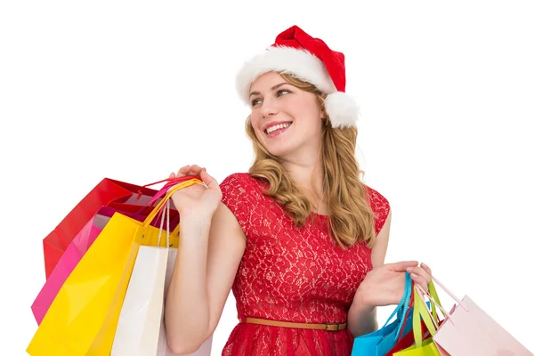 Loira sorridente em santa chapéu segurando sacos de compras — Fotografia de Stock