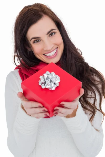 Felice bruna mostrando regalo rosso con un fiocco — Foto Stock