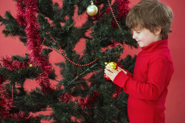 Festlicher kleiner Junge hängt eine Christbaumkugel auf — Stockfoto