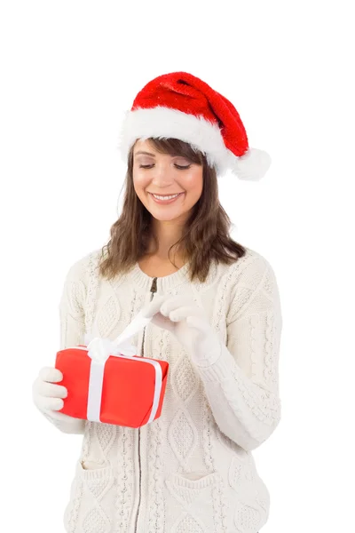 Bruna festiva in cappello di Babbo Natale che apre un regalo — Foto Stock