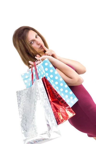 Bonita morena guardando un secreto sosteniendo bolsas de regalo —  Fotos de Stock