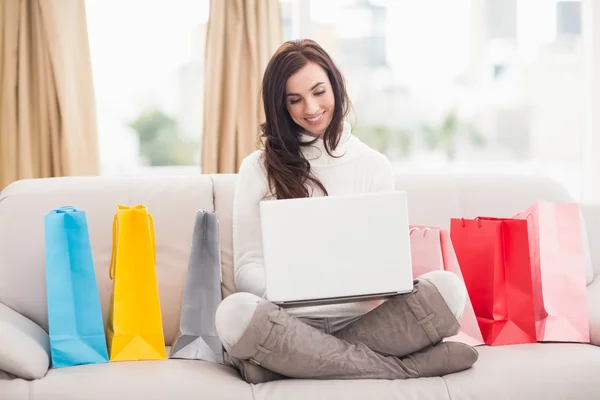 Skönhet brunett med sin laptop i soffan — Stockfoto