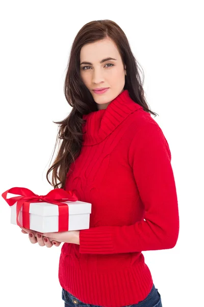 Morena sorridente em chapéu vermelho jumper segurando um presente — Fotografia de Stock