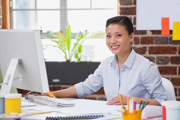 Smiling young woman working at desk — Stock Photo, Image