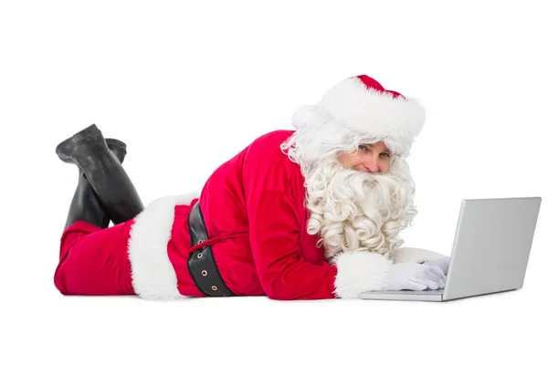 Gelukkig santa liggen en met behulp van laptop — Stockfoto