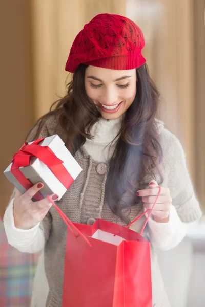 Gelukkig brunette geschenk te houden en op zoek in geschenk tas — Stockfoto