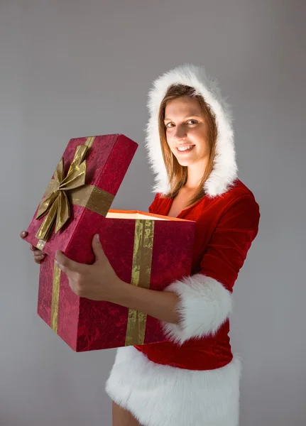 Lächelndes Mädchen, das ein Geschenk öffnet und in die Kamera blickt — Stockfoto