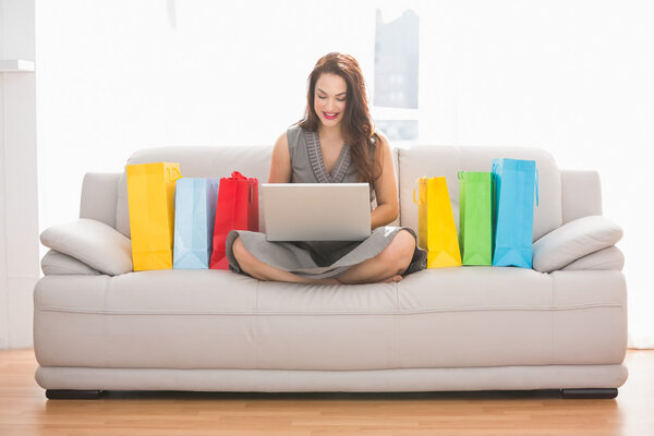 Belleza morena usando su portátil en el sofá — Foto de Stock