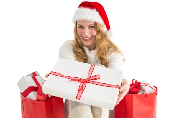 Frau mit Weihnachtsmütze bietet ein Geschenk an Stockfoto