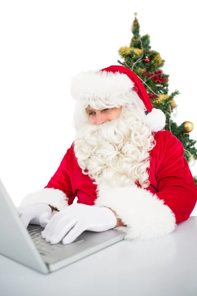 Weihnachtsmann mit seinem Laptop in der Nähe des Weihnachtsbaums — Stockfoto