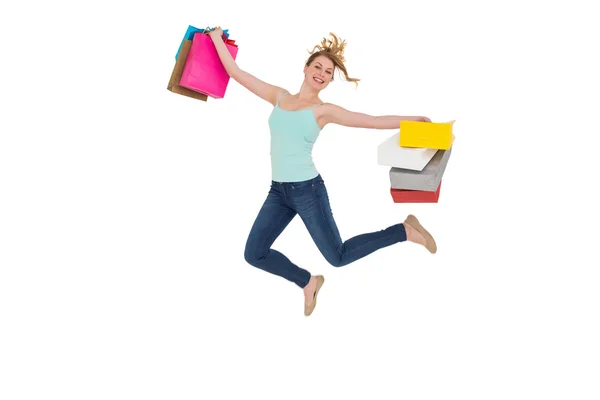 Excited blonde jumping while holding shopping bags — Stock Photo, Image