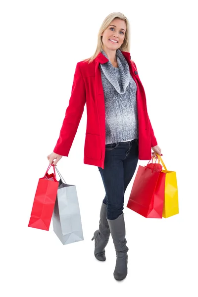 Happy blonde in winter clothes holding shopping bags — Stock Photo, Image