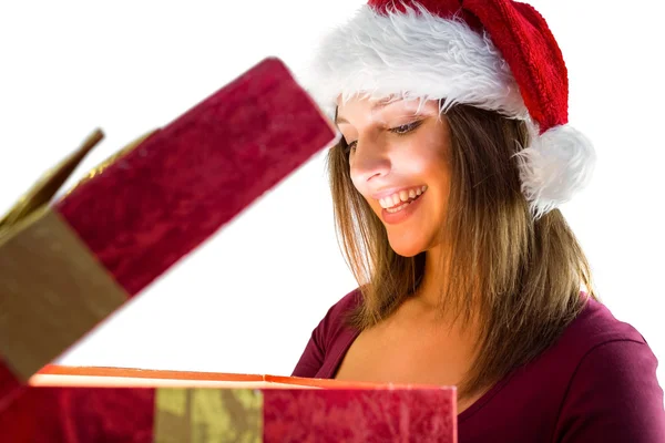 Bella bruna in cappello da Babbo Natale che apre un regalo — Foto Stock