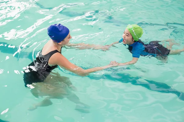 Милый мальчик учится плавать с тренером — стоковое фото