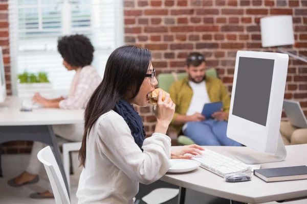 Casual woman drinking coffee while using computer — Stock Photo, Image