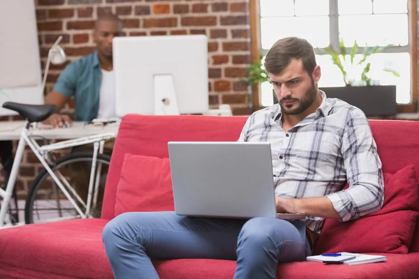 Casual man using laptop on couch — Stock Photo, Image