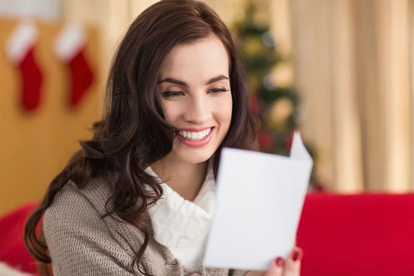 Sonriente morena en el sofá leyendo carta en Navidad —  Fotos de Stock