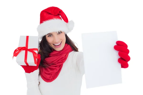 Morena festiva sosteniendo regalo y mostrando papel — Foto de Stock