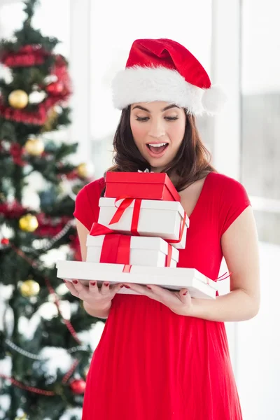 Überraschte Brünette im roten Kleid mit einem Stapel von Geschenken — Stockfoto