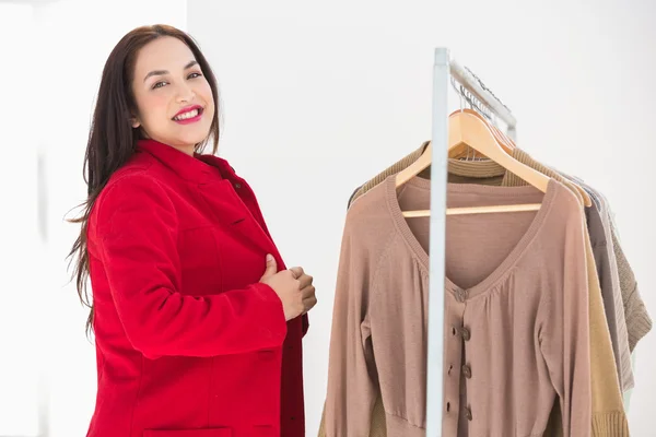 Smiling brunette trying the red coat — Stock Photo, Image