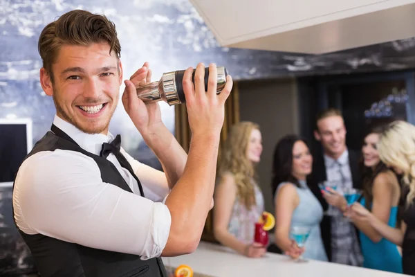 Bonito barman sorrindo para a câmera fazendo um coquetel — Fotografia de Stock