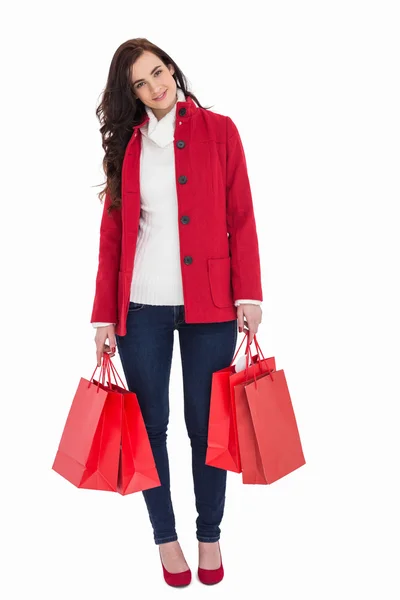 Lachende brunette in winter kleding bedrijf shopping tassen — Stockfoto