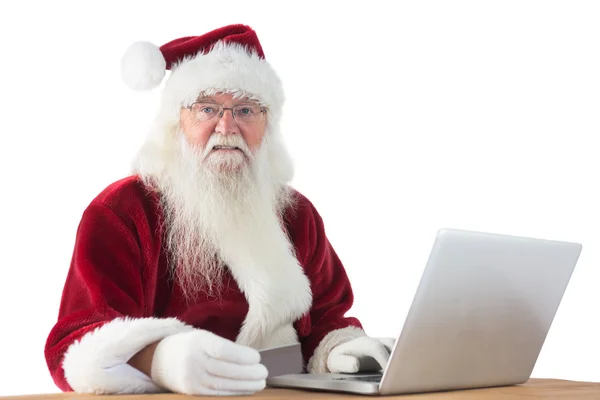Санта платит кредитной картой на ноутбуке — стоковое фото