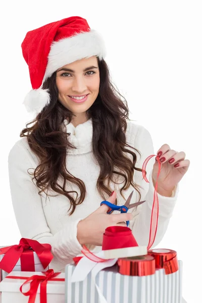 Smiling brunette in santa hat packing gifts — Stock Photo, Image