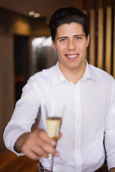 Schöner Mann lächelt in die Kamera und hält Champagner in der Hand — Stockfoto