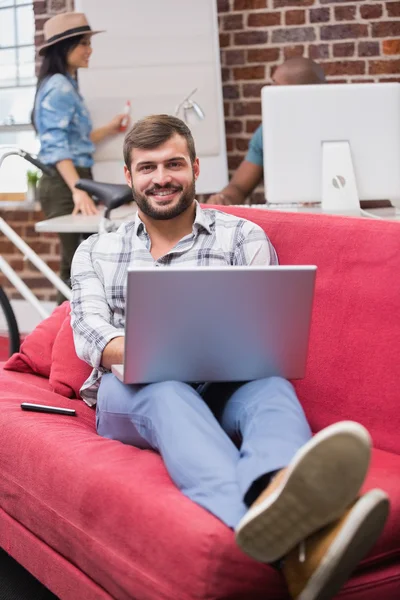 Чоловік використовує ноутбук на дивані в офісі — стокове фото