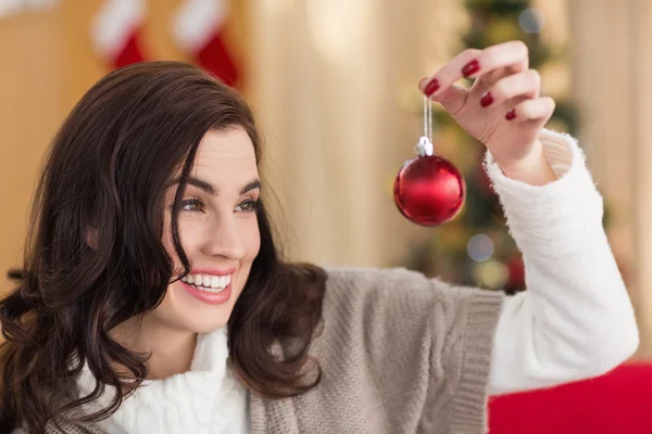 Sonriente morena sosteniendo una chuchería en Navidad —  Fotos de Stock