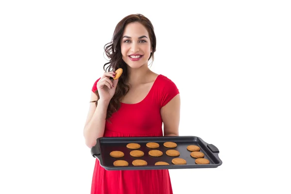Счастливая брюнетка ест горячее печенье — стоковое фото