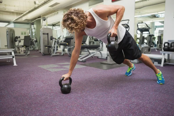 Hombre haciendo ejercicio con campanas de tetera en el gimnasio — Foto de Stock