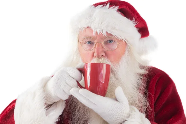 Santa bebe de una taza roja —  Fotos de Stock