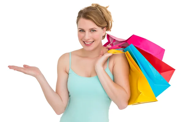 Smiling woman presenting while holding shopping bags — Stock Photo, Image
