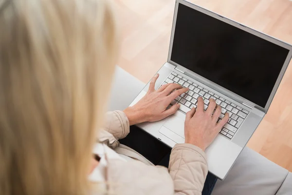 Donna bionda che utilizza il computer portatile sul divano — Foto Stock