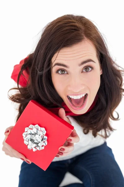 Excited brunette sitting holding red gift — Stock Photo, Image