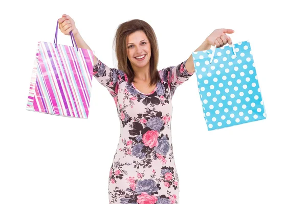 Young woman in floral dress holding up shopping bags — Stock Photo, Image