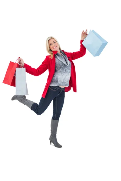 Happy blonde in winter clothes holding shopping bags — Stock Photo, Image