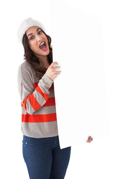 Excited brunette in santa hat showing white poster — Stock Photo, Image