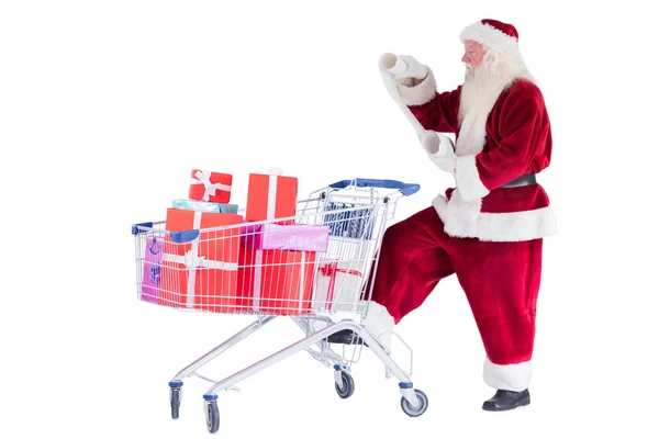 Weihnachtsmann schiebt beim Lesen einen Einkaufswagen — Stockfoto