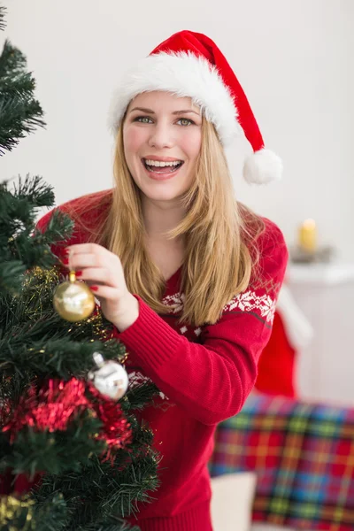 Улыбающаяся женщина вешает рождественские украшения на елку — стоковое фото